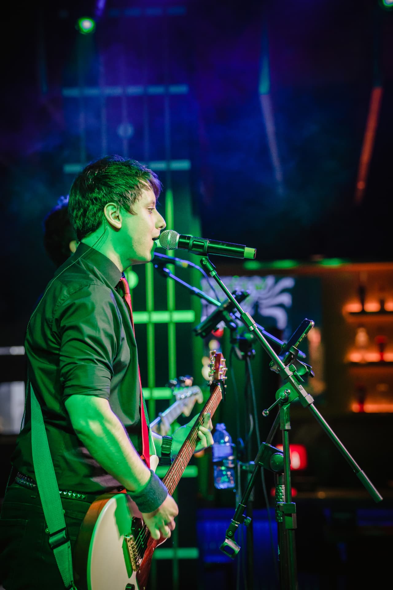 Vocalista da Drive cantando ao microfone com guitarra branca